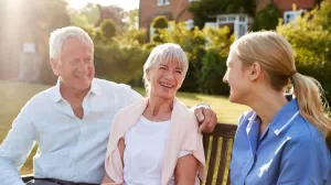 A husband and wife sitting on a bench with their granddaughter