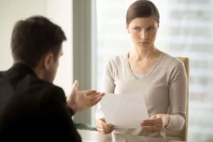 A woman holding a document and looking at a man in professional attire
