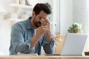 A frustrated man sitting in front of a laptop