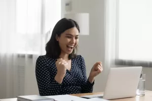 A woman excitedly looking at a laptop screen