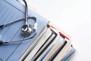 A stethoscope sitting on a stack of files and folders